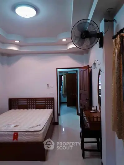 Cozy bedroom with modern ceiling fan and stylish furniture, perfect for relaxation.