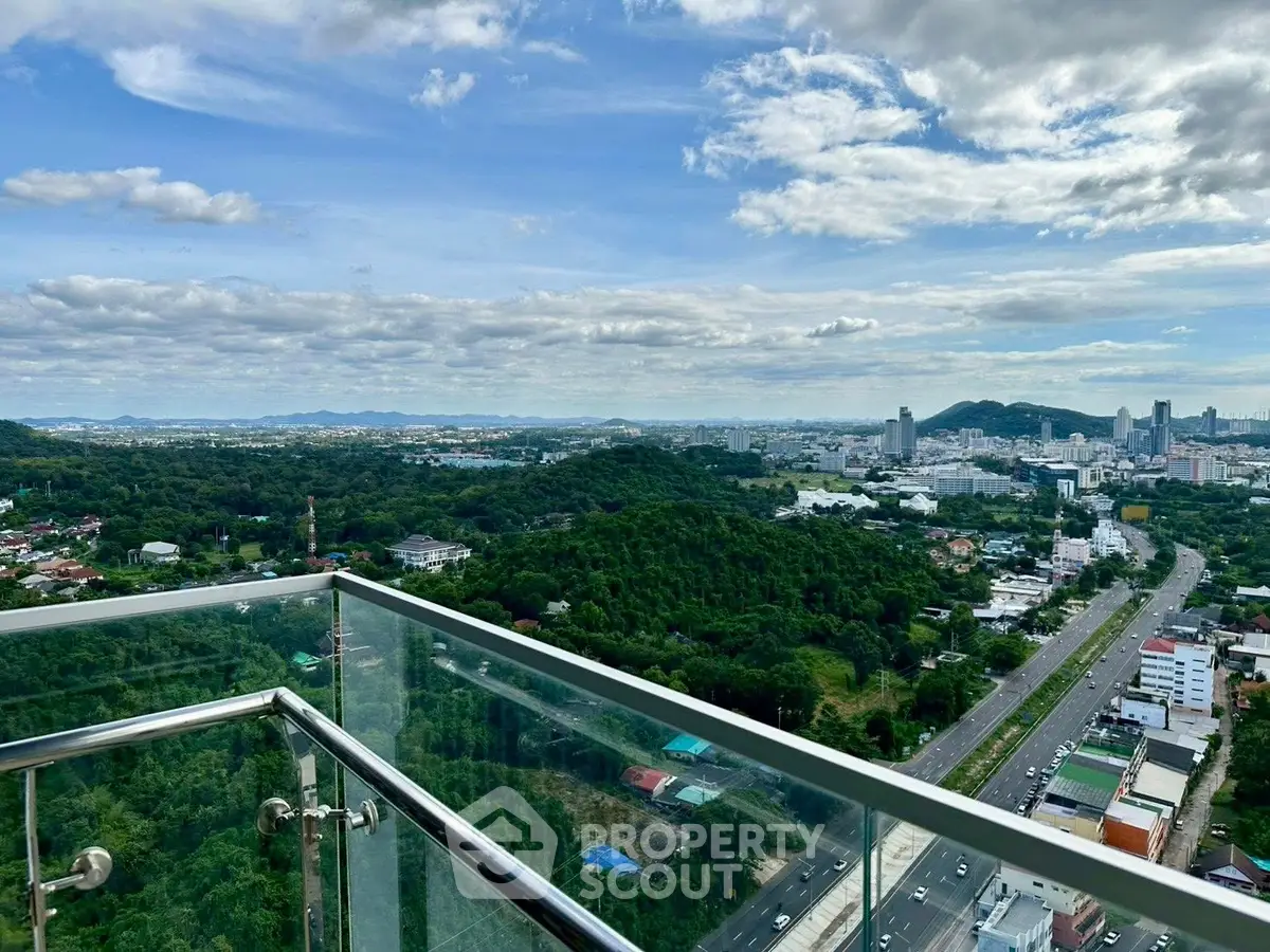 Stunning cityscape view from a high-rise balcony with glass railing.