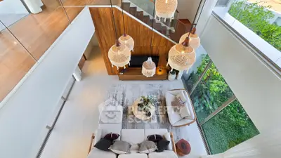 Stunning modern living room with high ceilings and large windows overlooking lush greenery.