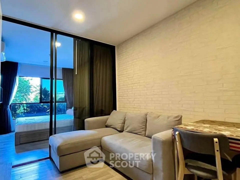 Modern living room with cozy sofa and view into bedroom through glass partition