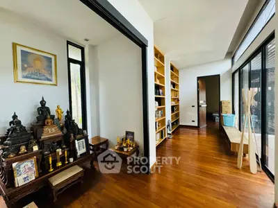 Spacious and serene living area with polished hardwood floors, traditional decor, and ample natural light from large windows, perfect for relaxation.