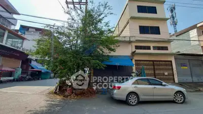 Street view of commercial building with parked car and tree, ideal for business opportunities.