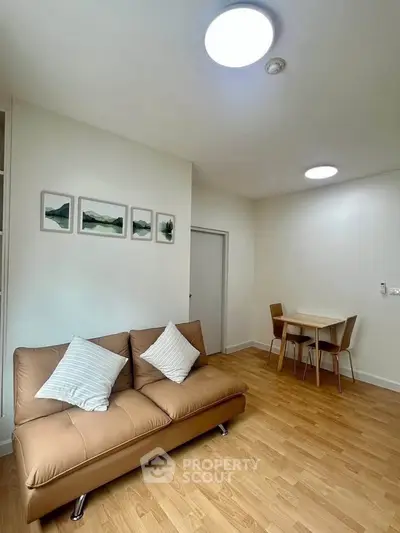 Modern living room with stylish sofa and dining area, featuring elegant wooden flooring and contemporary lighting.