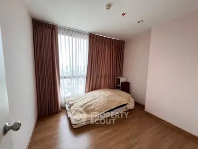 Cozy minimalist bedroom with large window and wooden flooring