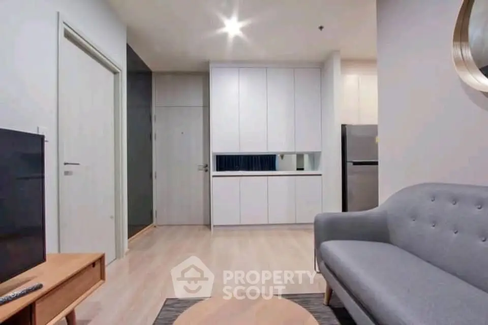 Modern living room with sleek furniture and integrated kitchen appliances in a stylish apartment.
