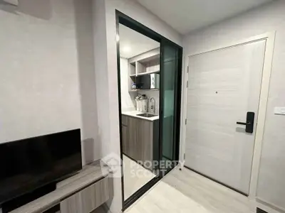 Modern compact kitchen with sleek cabinetry and sliding glass door in stylish apartment.