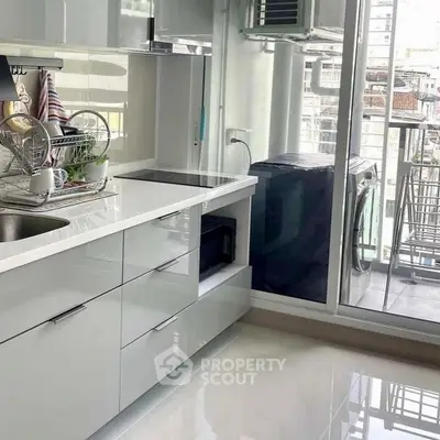 Modern kitchen with sleek white cabinets and balcony view