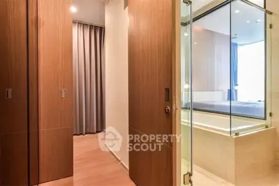 Modern bathroom with glass shower and wooden accents in luxury apartment.