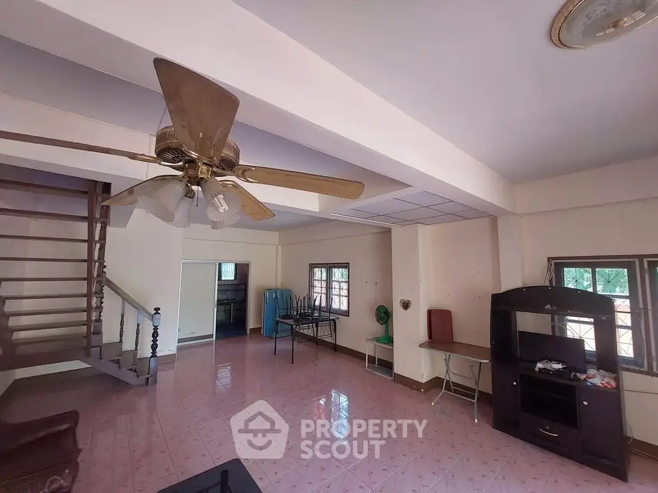 Spacious living room with ceiling fan and staircase in cozy home