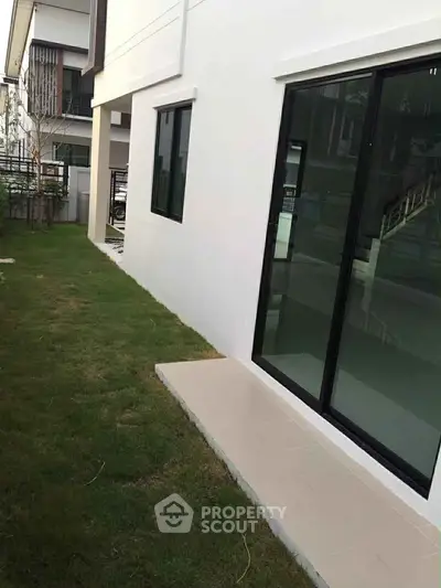 Modern residential exterior with sliding glass doors and lush green lawn