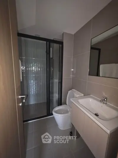 Modern bathroom with sleek design, featuring a glass shower enclosure and contemporary fixtures.