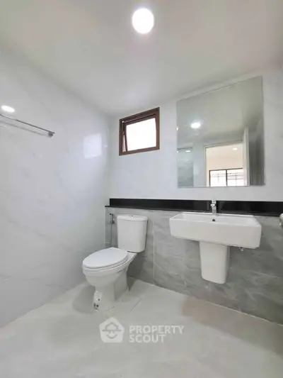 Modern bathroom with sleek fixtures and large mirror in a bright, minimalist design.