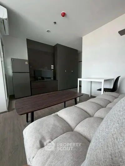 Modern living room with sleek furniture and open kitchen layout in a stylish apartment.