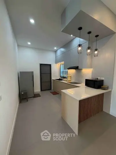 Modern kitchen with sleek design, featuring pendant lights and compact appliances, perfect for urban living.
