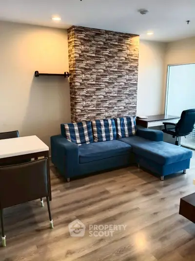 Modern living room with stylish stone accent wall and cozy blue sectional sofa.