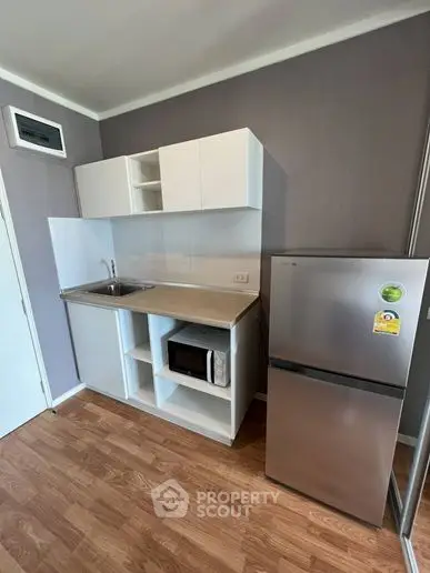 Modern compact kitchen with sleek cabinetry and stainless steel fridge