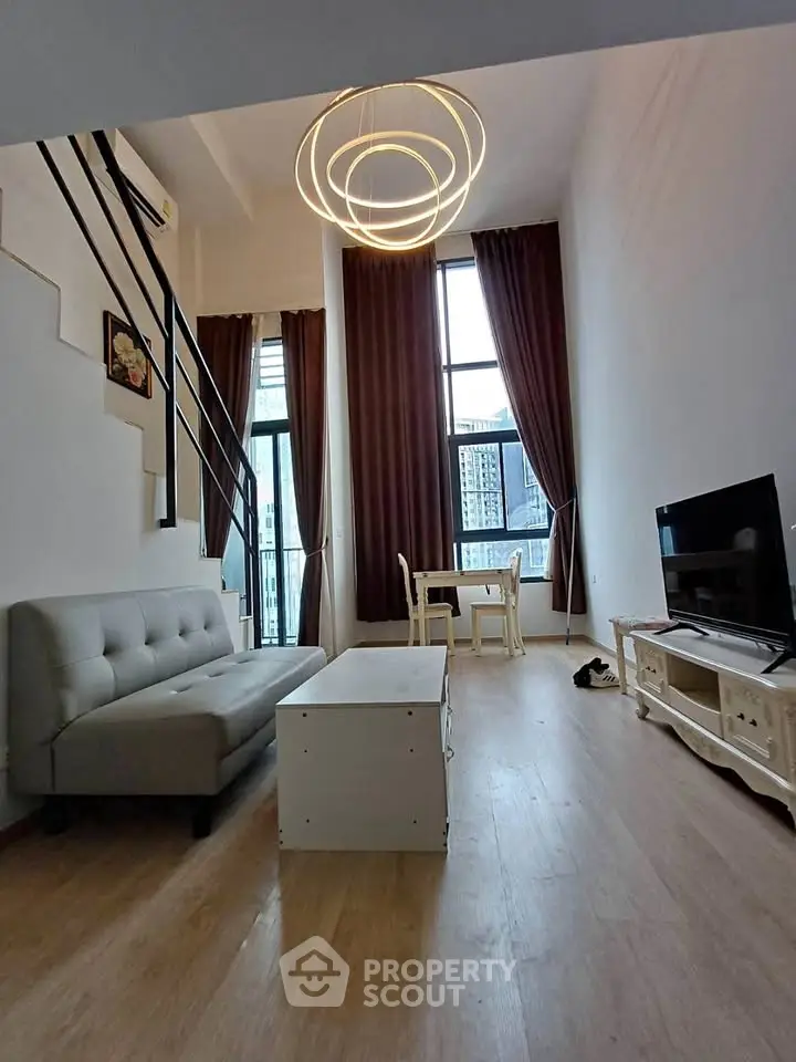 Modern loft-style living room with high ceilings and large windows offering city views.