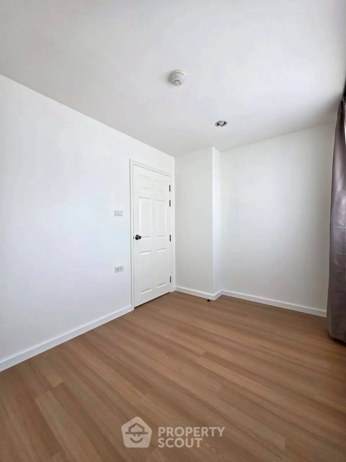 Minimalist empty room with wooden flooring and white walls, ready for customization.