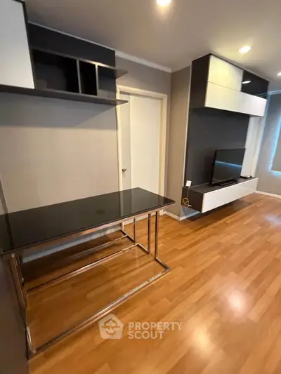 Modern living room with sleek furniture and wooden flooring, featuring a stylish TV unit and workspace.