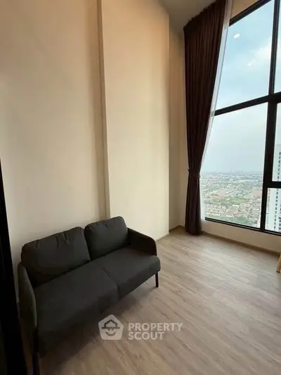 Spacious living room with large window offering stunning city view, featuring modern sofa and elegant curtains.