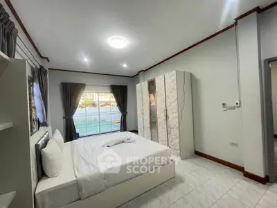 Spacious bedroom with modern decor and large window offering natural light.
