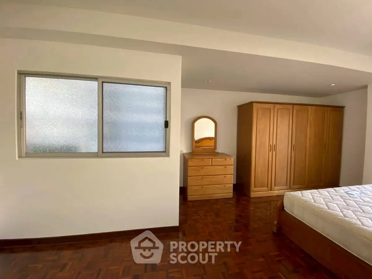 Spacious bedroom with wooden furniture and parquet flooring