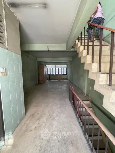 Spacious interior with staircase and large windows, ideal for renovation or creative use.