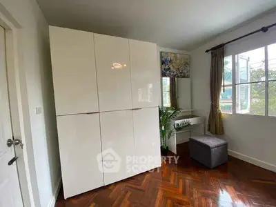 Bright bedroom with large wardrobe and wooden flooring