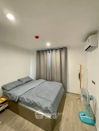 Cozy bedroom with modern decor and natural light, featuring a comfortable bed and air conditioning.