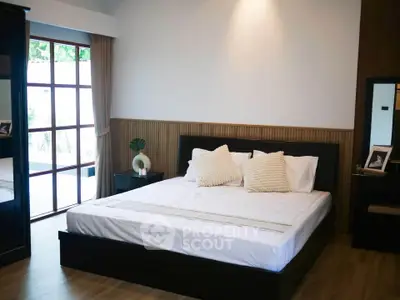 Spacious bedroom with modern decor and large window for natural light.