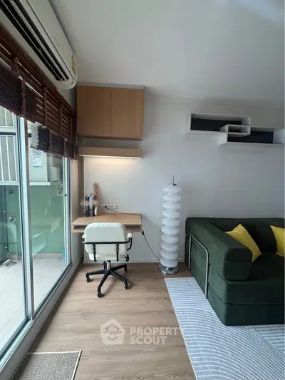 Modern living room with stylish furniture and balcony access, featuring a cozy workspace and elegant decor.