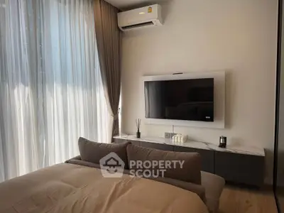 Modern bedroom with sleek TV setup and elegant curtains, showcasing contemporary interior design.