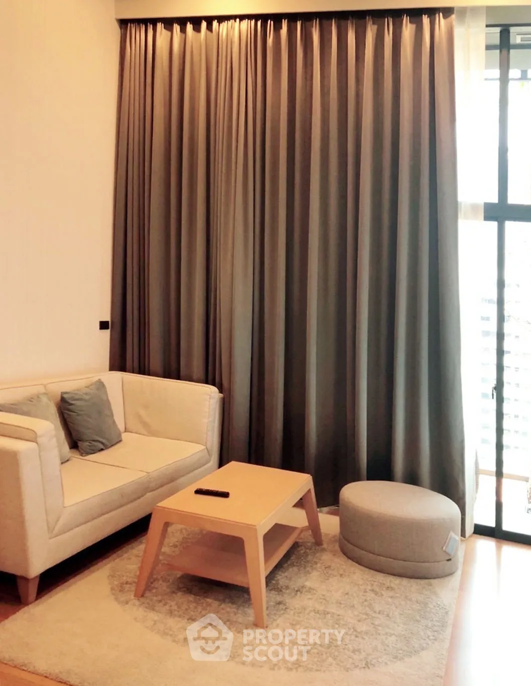 Cozy living room with modern sofa, stylish coffee table, and elegant curtains in a bright apartment.