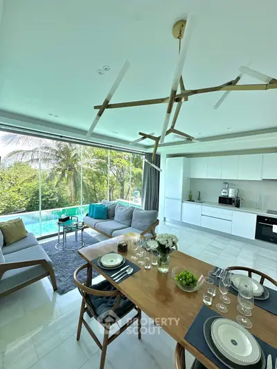 Luxurious open-plan living room with modern kitchen and pool view, perfect for entertaining.
