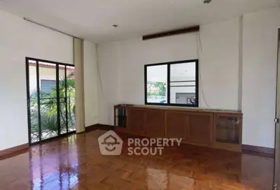 Spacious living room with polished wooden floors and large windows for natural light.