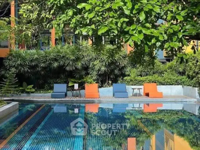 Luxurious outdoor pool area with vibrant lounge chairs and lush greenery, perfect for relaxation and leisure.