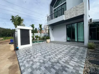 Modern house exterior with spacious tiled patio and lush garden view.