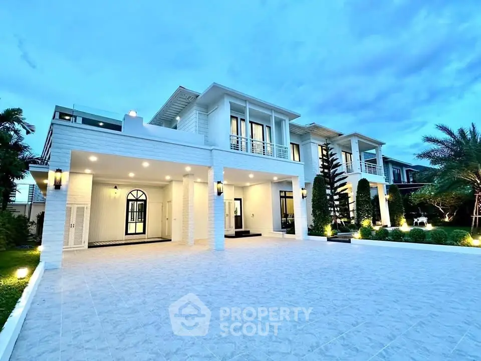 Luxurious modern villa with spacious driveway and elegant exterior lighting.