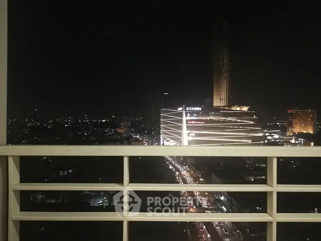 Stunning night cityscape view from a high-rise balcony, showcasing vibrant city lights and modern architecture.