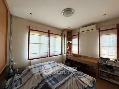 Cozy bedroom with natural light, featuring built-in shelves and air conditioning for comfort.