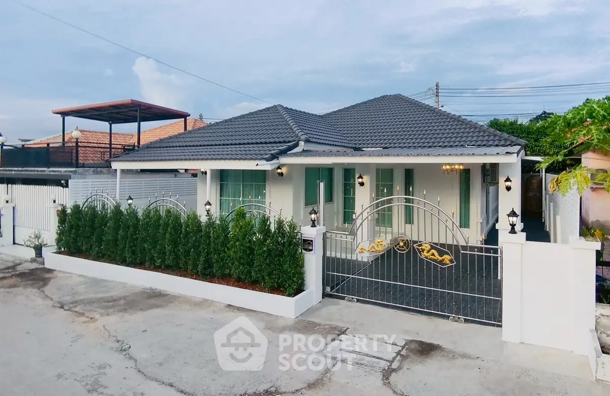 Charming single-story home with modern design and gated entrance, featuring lush greenery and a sleek roof.
