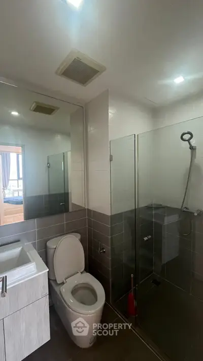 Modern bathroom with glass shower and sleek fixtures in contemporary home.