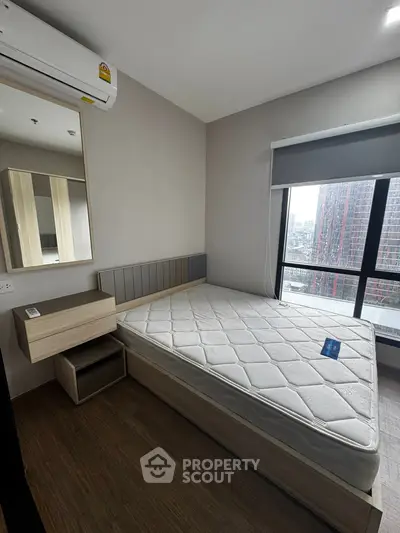 Modern bedroom with large window and city view, featuring a comfortable bed and stylish decor.