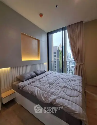 Modern bedroom with large windows offering stunning city views and elegant decor.