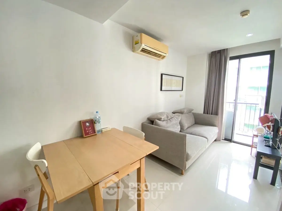 Modern living room with cozy sofa, dining table, and balcony access in bright apartment.