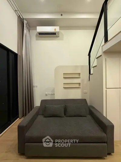 Modern living room with stylish gray sofa and loft design, featuring sleek air conditioning and elegant decor.