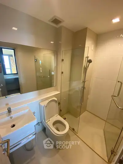 Modern bathroom with glass shower and sleek fixtures in a contemporary apartment.