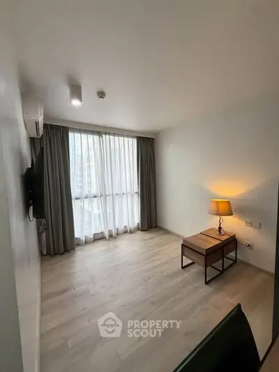 Modern living room with large window and minimalist decor in urban apartment.