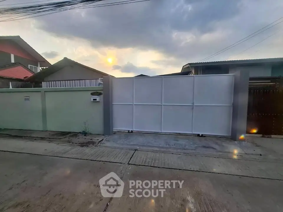 Modern residential entrance with white gate and sunset view