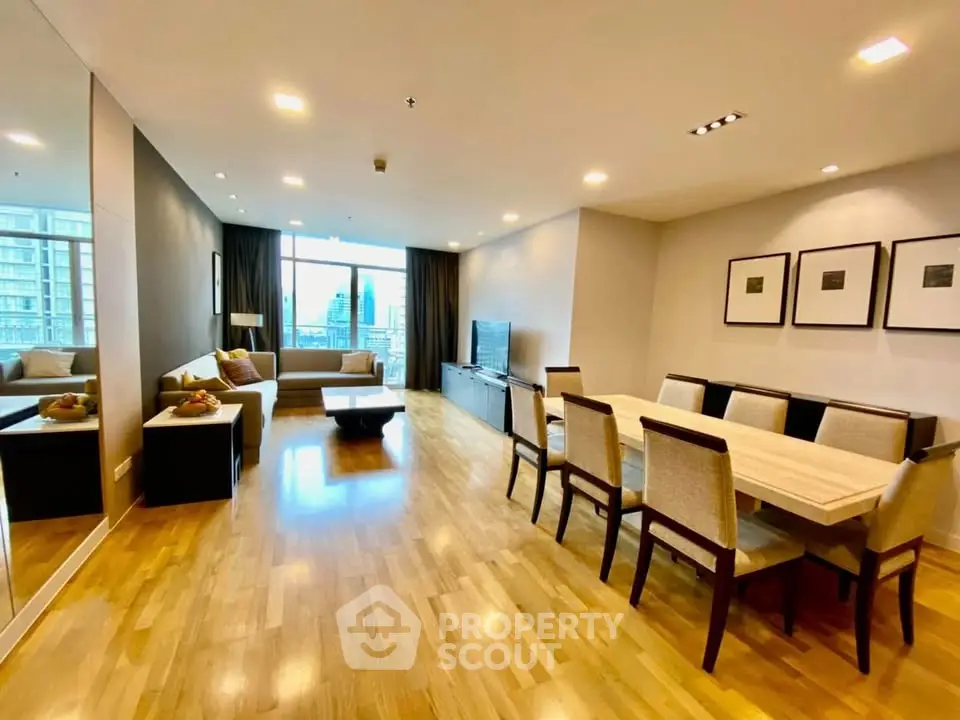 Spacious modern living room with dining area and city view, featuring elegant decor and hardwood floors.